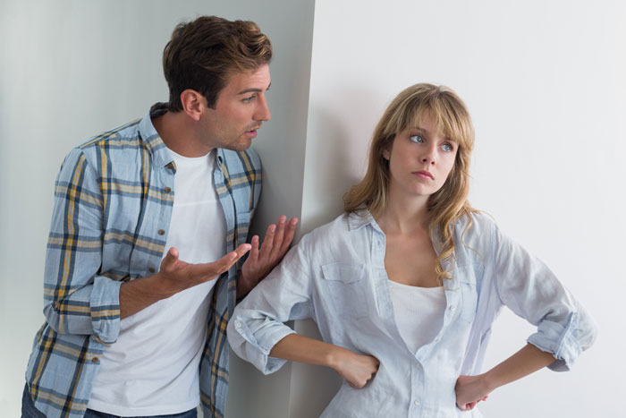 Young couple arguing inside home, boyfriend expressing concern as girlfriend looks frustrated and distant. Young couple arguing inside home, boyfriend expressing concern as girlfriend looks frustrated and distant.