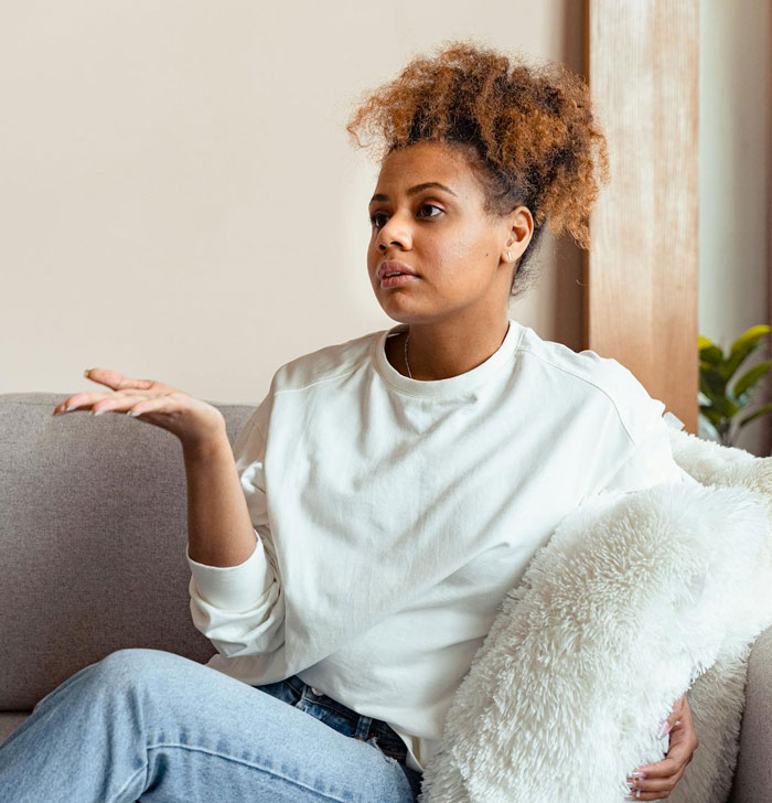 Young woman sitting on a couch, looking frustrated and unsure while discussing a break-up with a guy after a romantic trip. Young woman sitting on a couch, looking frustrated and unsure while discussing a break-up with a guy after a romantic trip.