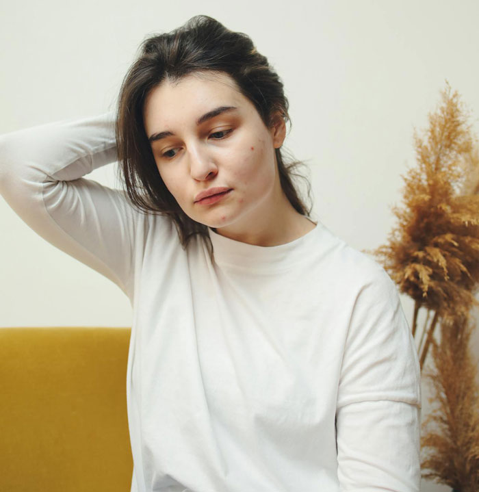 Young woman in a white shirt looking down thoughtfully, reflecting on a breakup after a romantic trip with a female friend. Young woman in a white shirt looking down thoughtfully, reflecting on a breakup after a romantic trip with a female friend.
