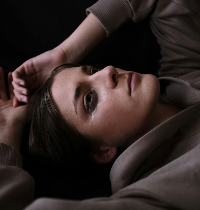 Close-up of a woman lying down with tears on her face, reflecting pain from a difficult break-up situation. Close-up of a woman lying down with tears on her face, reflecting pain from a difficult break-up situation.