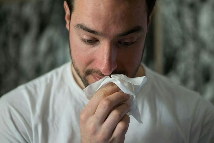 Man with mysterious medical issues holding a tissue to his nose, reflecting on symptoms before diagnosis clarity.