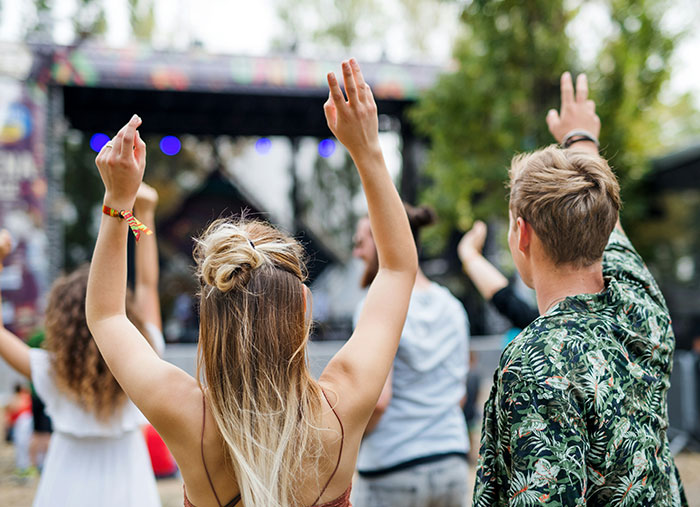Group of young people raising hands at outdoor event, embodying unexpected stories of a bad day turning life-changing.