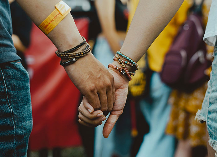 Two people holding hands, wearing bracelets, symbolizing unexpected stories of life-changing moments on a bad day.