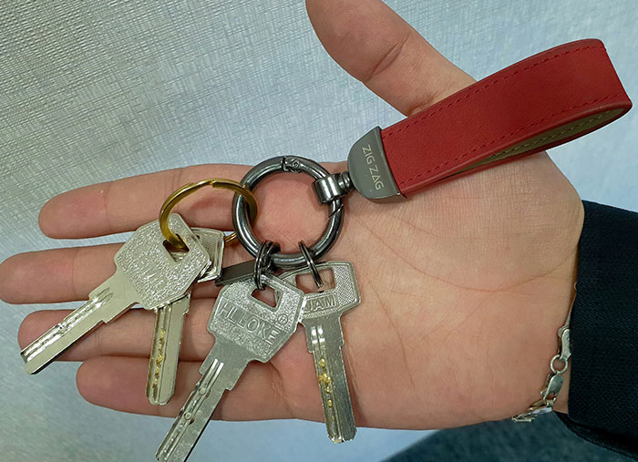 Hand holding a keyring with multiple keys and a red ZigZag keychain symbolizing unexpected stories of change.
