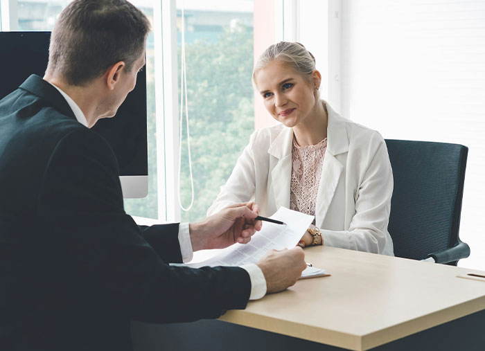 Man and woman discussing documents in office, illustrating unexpected stories of how a bad day turned into a life-changing one.