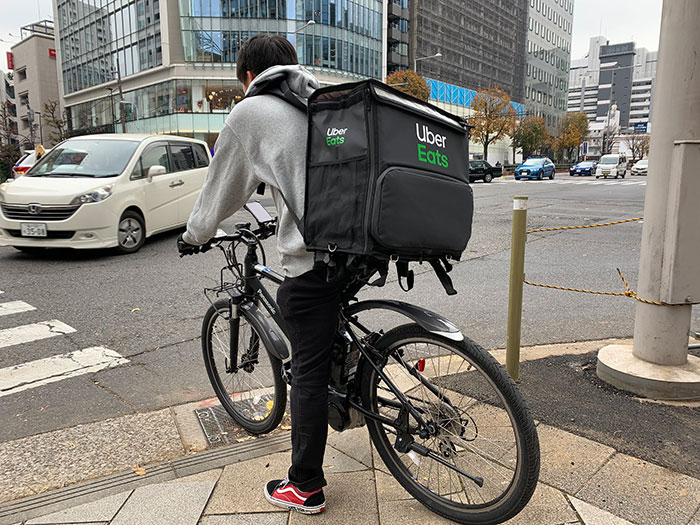 Delivery rider on a bike with Uber Eats bag navigating a busy urban street, illustrating businesses that lost clients.