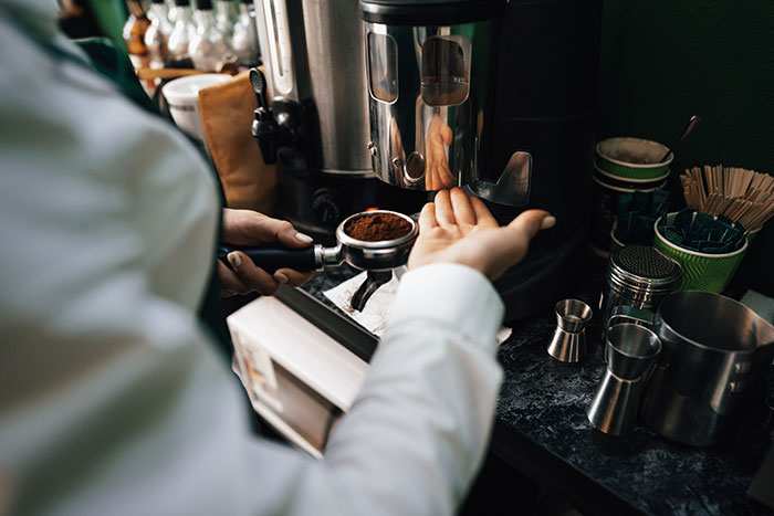 Barista preparing espresso with coffee grounds in a busy coffee shop, illustrating businesses that lost clients with poor decisions.