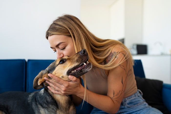Young woman showing affection to her dog in a cozy home setting, symbolizing loyal client relationships in business.