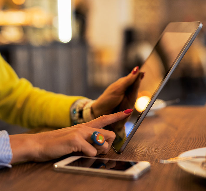 Person using a tablet at a wooden table with a smartphone nearby, illustrating businesses that lost clients with decisions.