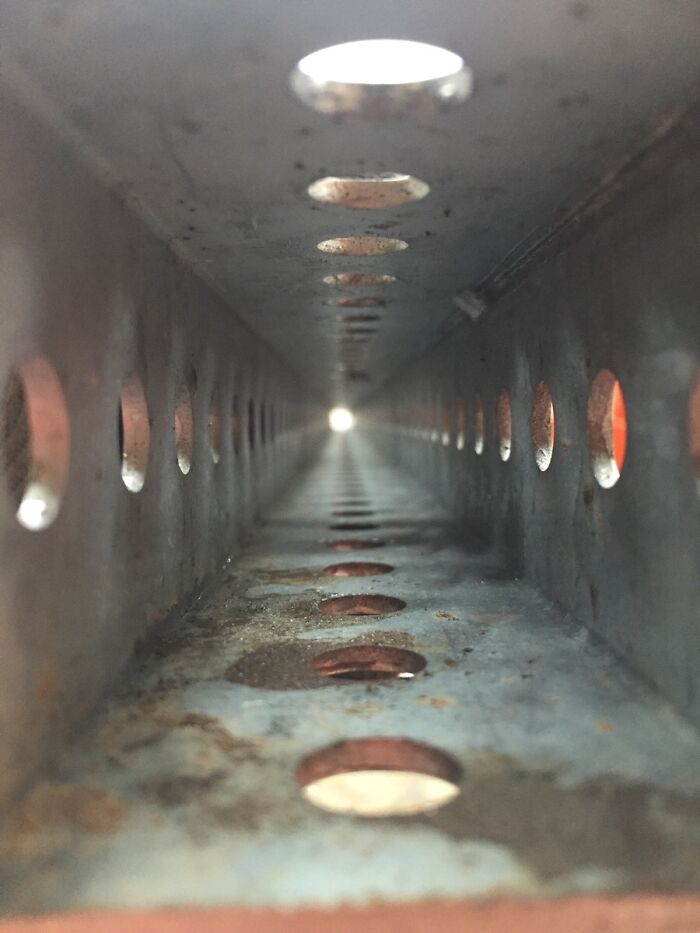 Close-up view of the insides of a perforated metal object showing rust and circular holes aligned in rows.