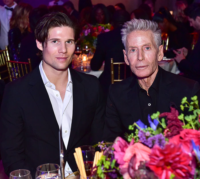 Calvin Klein, 83, and his boyfriend, 36, dressed formally at a crowded event with floral table decorations.