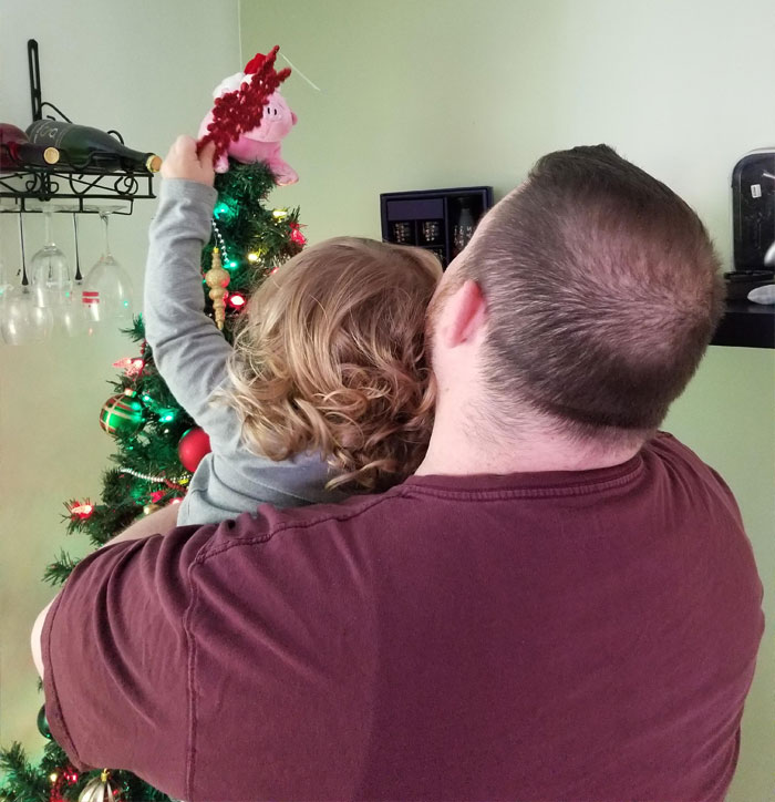 Father and child decorating a Christmas tree, reflecting the father&rsquo;s struggle with affording Christmas this year.