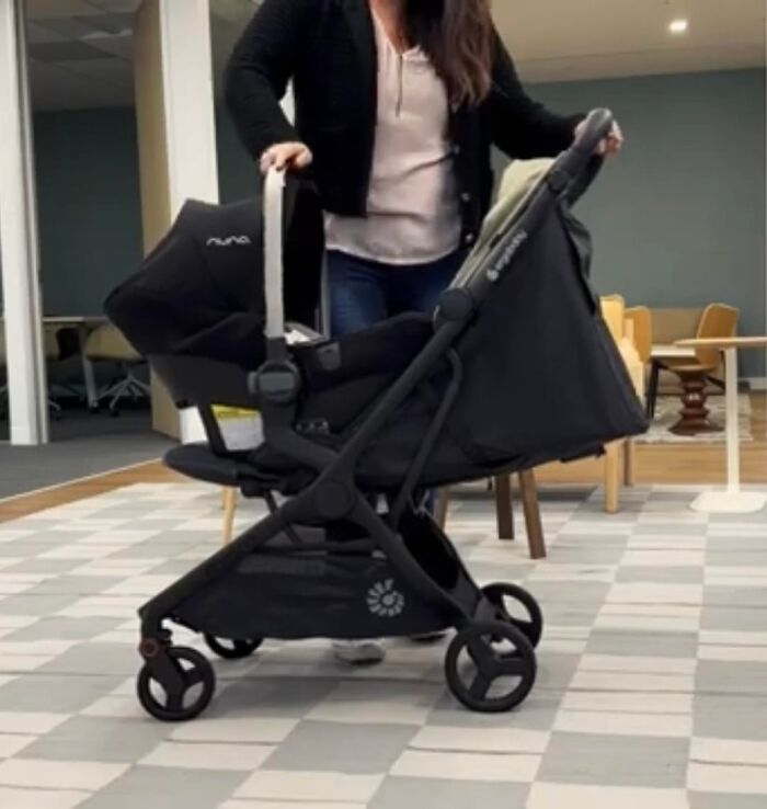 Woman pushing a black stroller indoors with a focus on comfort and convenience in a modern space.