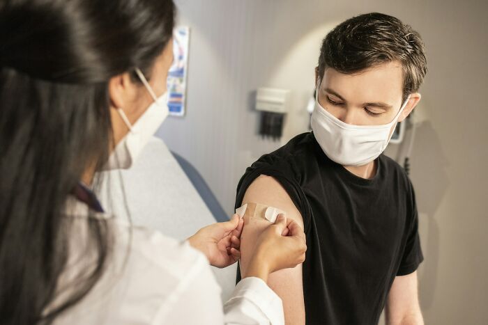 Healthcare professional applying bandage on patient's arm after vaccine, illustrating what many internet users think is a scam but isn’t.