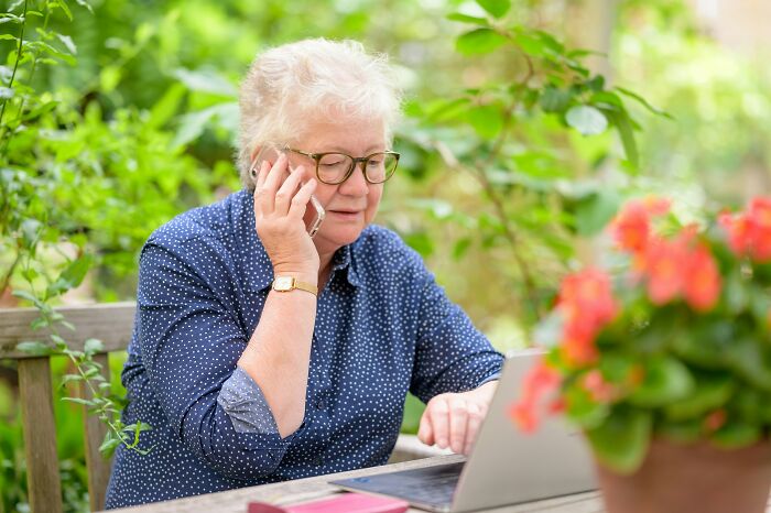 Older woman outdoors using laptop and phone, illustrating times people fell for scams and their impact.