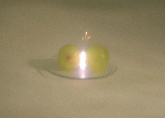 Two green grapes on a plate with a bright flare of chaotic light, creating an unusual and chaotic scene.