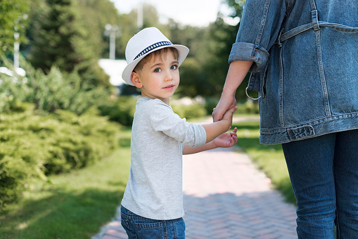 Young boy in a white hat holding an adult&rsquo;s hand outdoors, reflecting blended family and in-laws Christmas tension.