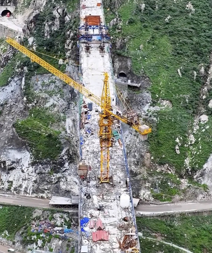 Aerial view of China's ambitious bridge collapsing into dust months after opening, showing debris and a yellow construction crane. Aerial view of China's ambitious bridge collapsing into dust months after opening, showing debris and a yellow construction crane.