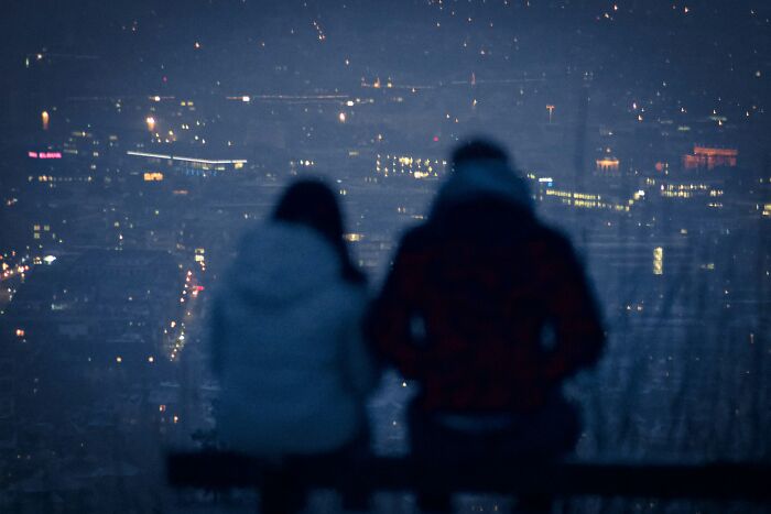 Two people sitting on a bench overlooking a city at night, reflecting the story about rehoming a dog abroad. Two people sitting on a bench overlooking a city at night, reflecting the story about rehoming a dog abroad.