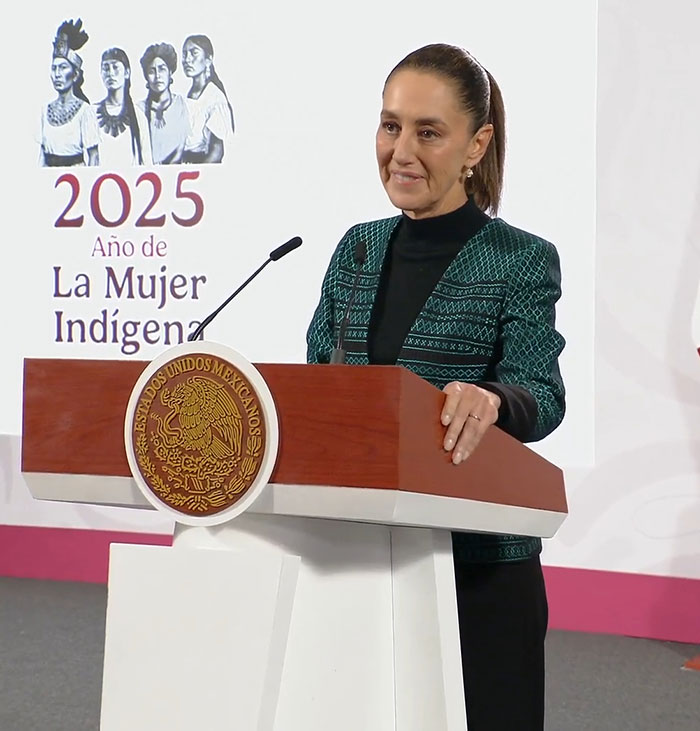 Mexican president speaking at podium during event on indigenous women in 2025 with emblem of Estados Unidos Mexicanos visible.