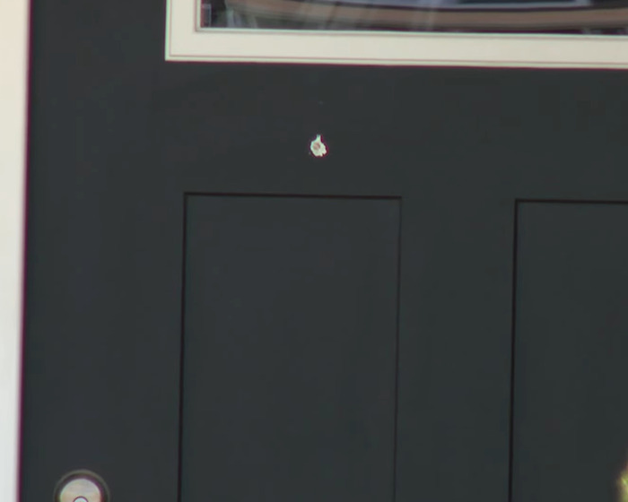 Close-up of a dark front door with a damaged spot, symbolizing tragedy related to a cleaning lady's innocent mistake.