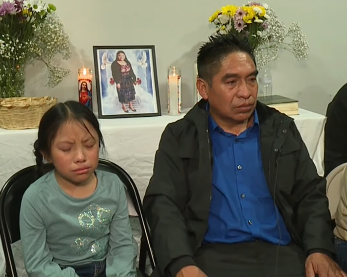 Mourning family members sitting beside a memorial with photo and candles for cleaning lady lost tragically.