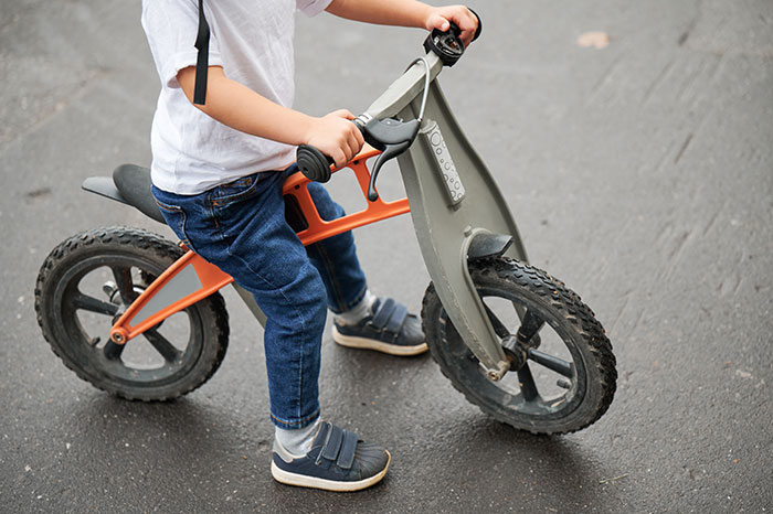 Young boy on a balance bike at the playground, highlighting issues of bullying and gender-based discipline refusal.