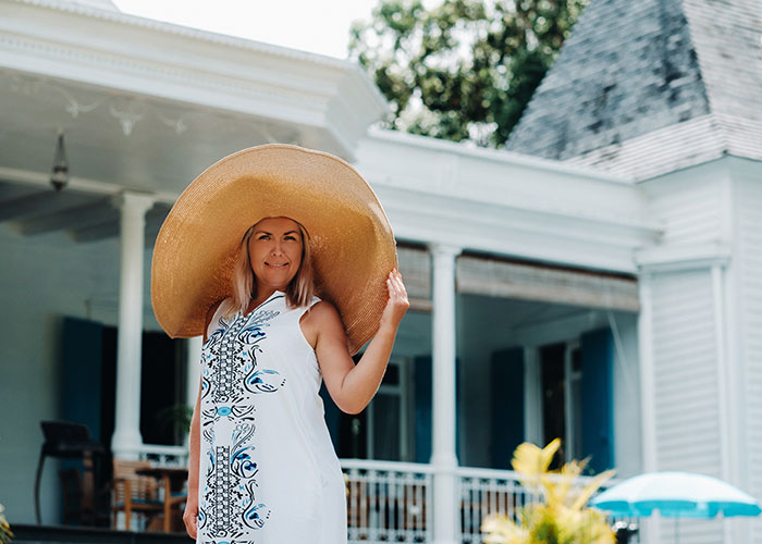 Woman in a large sunhat and white dress enjoying life outdoors, illustrating the debate on life in the USA versus Europe.