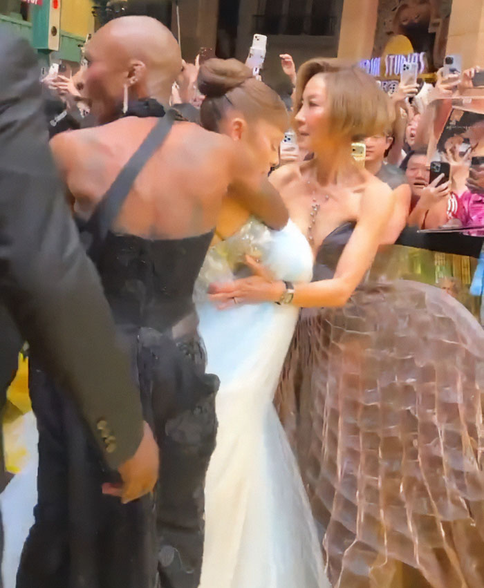 Michelle Yeoh at premiere wearing wasp nest inspired outfit, surrounded by crowd taking photos and videos.