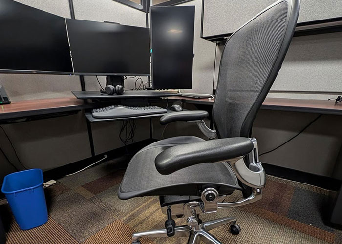 Ergonomic $1.8K office chair in a modern cubicle with multiple computer monitors and keyboard setup. Ergonomic $1.8K office chair in a modern cubicle with multiple computer monitors and keyboard setup.