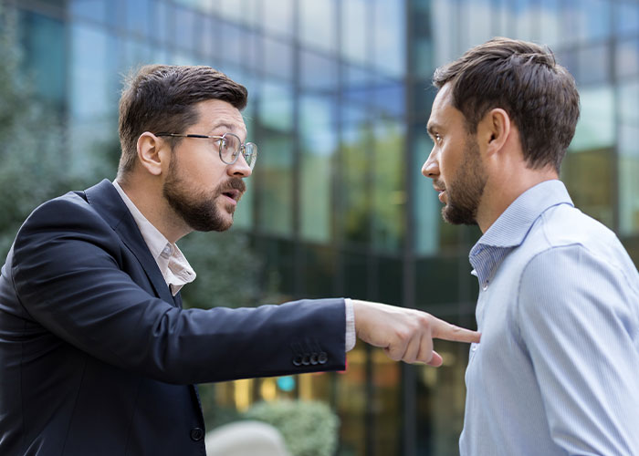 Man angrily confronting coworker outside office building, highlighting conflict over $1.8K office chair issue Man angrily confronting coworker outside office building, highlighting conflict over $1.8K office chair issue