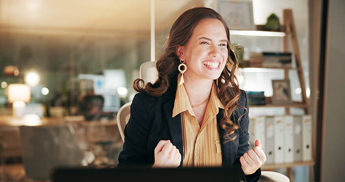 Woman in an office celebrating confidently after an office swap, highlighting employee frustration and coworker conflict.
