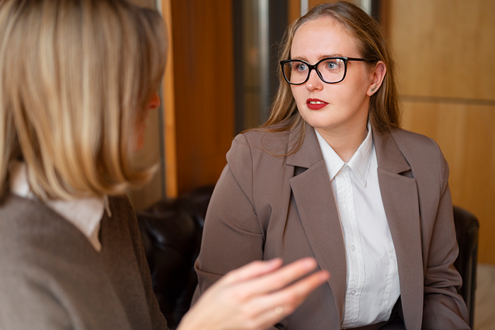 Two female employees in an office having a tense conversation during a frustrating office swap situation.