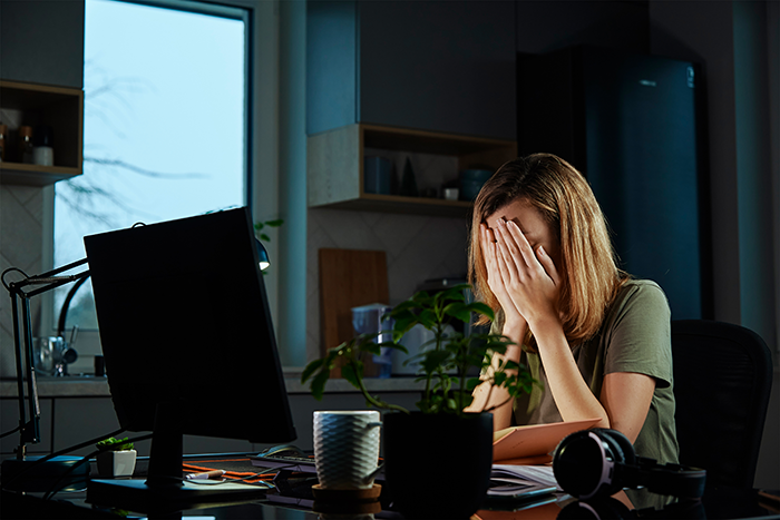 Frustrated coworker in office covering face in tears after employee takes everything during office swap conflict at workstation.