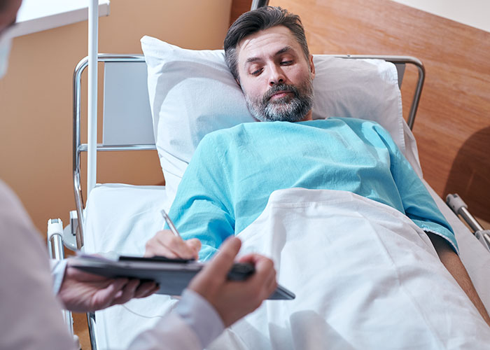 Patient in hospital bed wearing blue gown during consultation, illustrating weird and crazy ER stories experience.