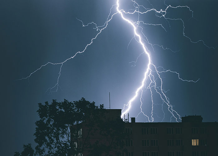 Lightning striking near a building at night, illustrating dramatic scenes from weird and crazy ER stories.