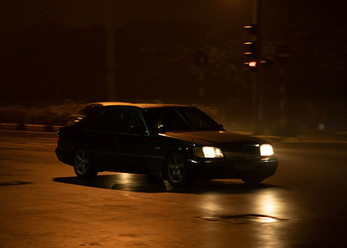 Black car driving at night on a dimly lit street, representing narrowly avoided kidnapping and disturbing internet threads.