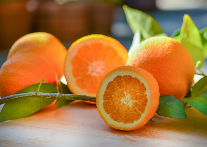 Close-up of fresh oranges with leaves on a wooden surface illustrating common words etymology and origins.