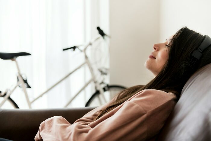 Young woman wearing headphones relaxing on a couch, symbolizing stories of families and the golden child experience.
