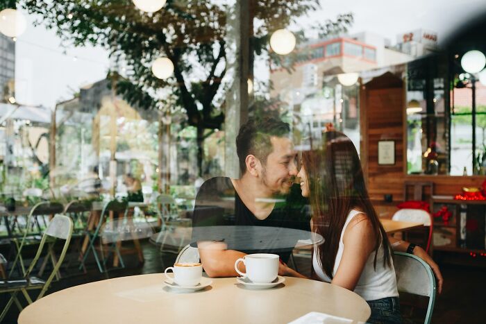 Couple sharing an intimate moment in a cafe, illustrating funny moments people wanted to say but accidentally hurt loved ones.