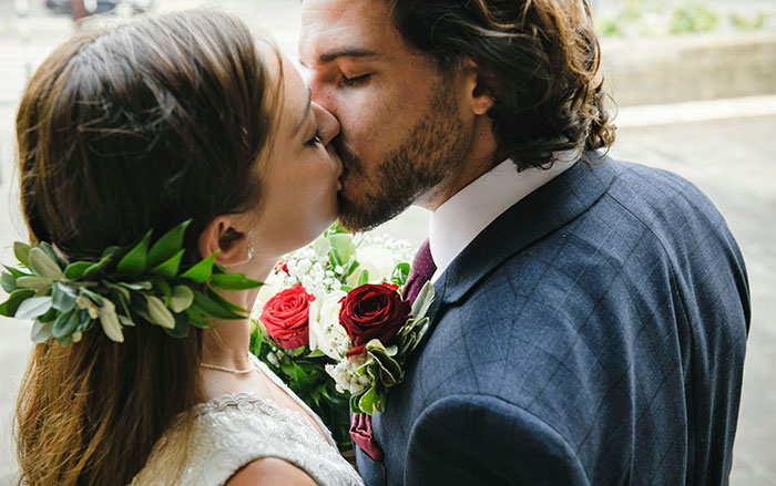 Bride and groom sharing a kiss at wedding with bouquet, highlighting bride breaking no dating rule during break. Bride and groom sharing a kiss at wedding with bouquet, highlighting bride breaking no dating rule during break.