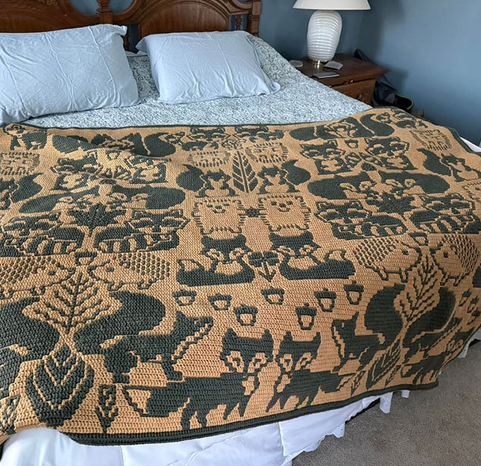 Crochet blanket featuring intricate woodland animals and nature patterns displayed proudly on a bed by crochet enthusiasts.