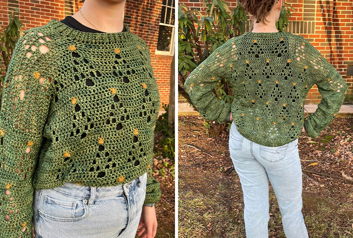 Green crocheted sweater with floral accents worn by person standing outdoors, showcasing detailed crochet project by enthusiasts.