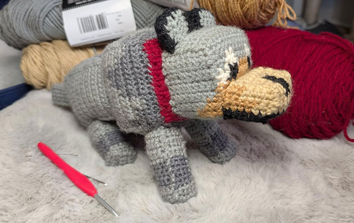 Crochet enthusiast's detailed amigurumi dog project displayed with yarn and a crochet hook on a soft surface.