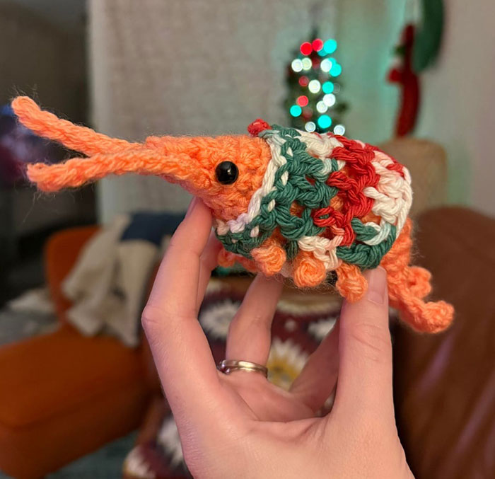 Hand holding a small colorful crochet animal, showcasing a proud crochet enthusiast’s detailed project creation.