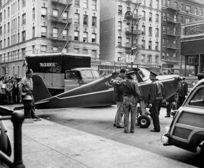 Small vintage airplane on a city street with police and onlookers, illustrating comically absurd facts unknown to many.
