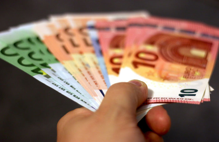 Hand holding a fan of colorful Euro banknotes symbolizing inheritance and financial disputes in family matters.