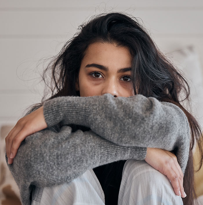 Teen girl in a gray sweater looking sad and contemplative, symbolizing teen leaves home after dad chooses girlfriend over her.