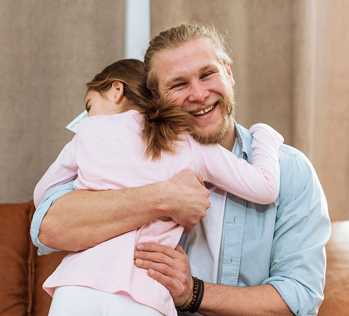 Man smiling warmly while hugging a young girl, illustrating themes of teen leaving home and adoption choice conflict.
