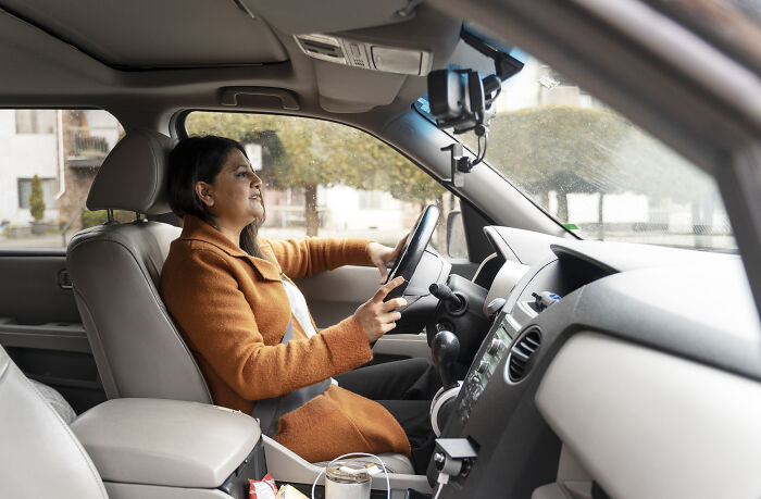 Woman driving a car on a rainy day, highlighting dangers of water and wet road conditions on driving safety.